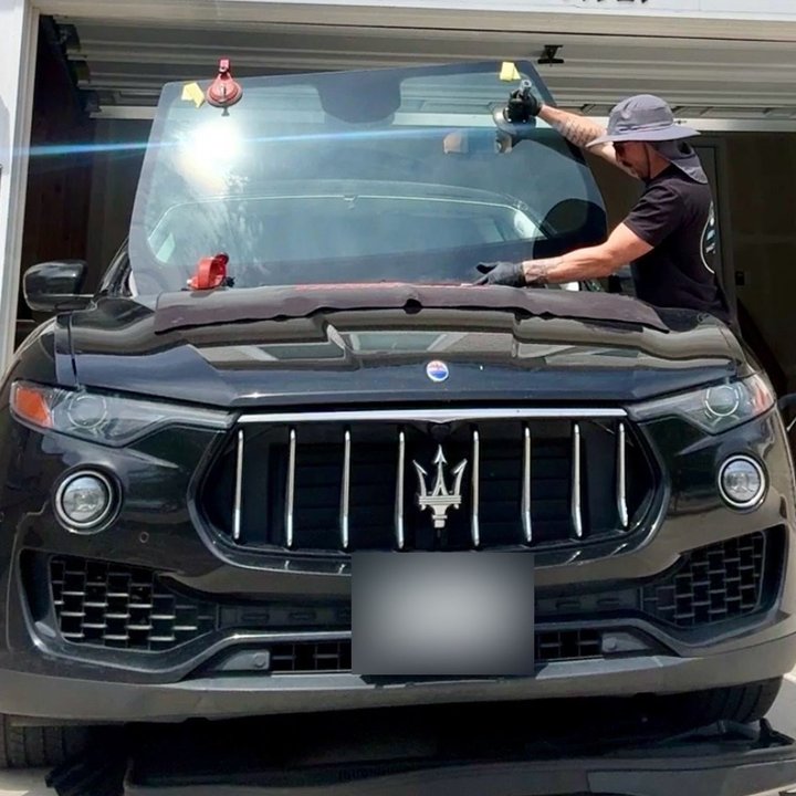 Jonathan Nation, Master Technician and owner of Shattered Vision Auto Glass, setting a new windshield onto a Maserati SUV in Colorado Springs